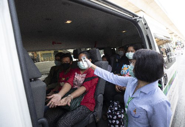 泰国卫生官周四在曼谷的一个健康检查站，向一辆客货车的乘客测量体温。（美联社）