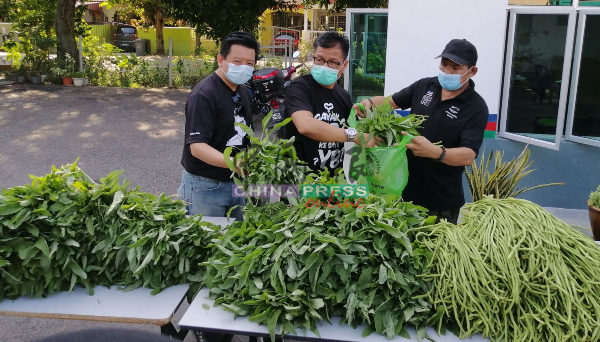 诺依占（中）把蔬菜包装好，方便派发给受惠的家庭。