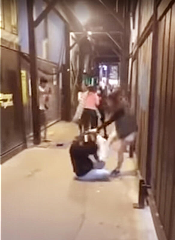 一名女袭击者伸脚踢向坐在地上的女子。（取自网络）