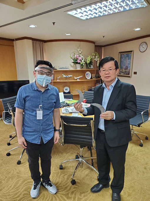 黄松毅（左）向槟州首长曹观友介绍，以3D技术打印出来的可拆式防护透明面罩。（受访者提供）