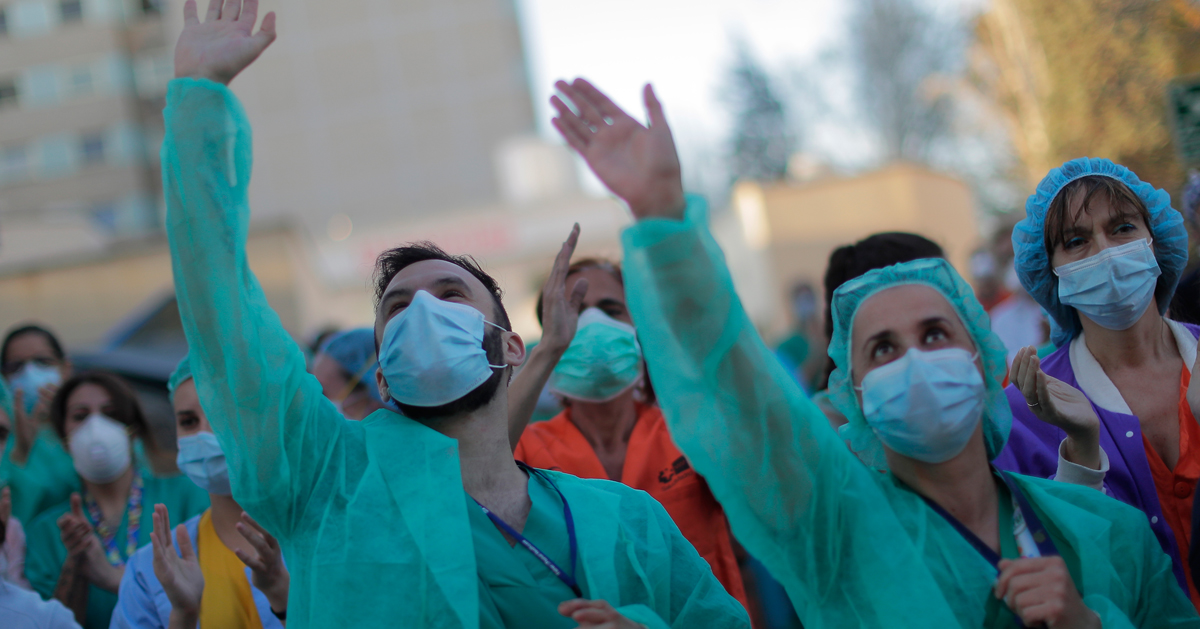 马德里医护人员周三在医院外向鼓掌的民众挥手