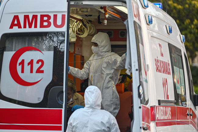 身穿防护服的救护人员，周日在伊斯坦布尔的一辆救护车内照顾一名疑似感染新冠肺炎的患者。（法新社）