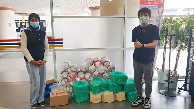 林铠文（右）将优大捐赠的1000个防护面罩移交给国大医院执行长办公室高级经理雅诗敏。
