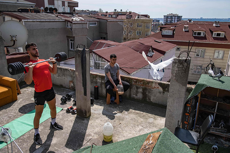 土耳其实施周末宵禁，民众无法外出，伊斯坦布尔一名男子周日到屋顶举重打发时间。（法新社）