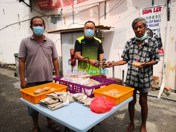 赖庆中（左2）移交免费食物给老人。左为梁证法。