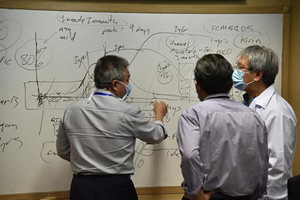 阿汉峇峇（左）和专家，站在写满方程式的白板前讨论疫情的照片，网民都在猜测他们在讨论什么。