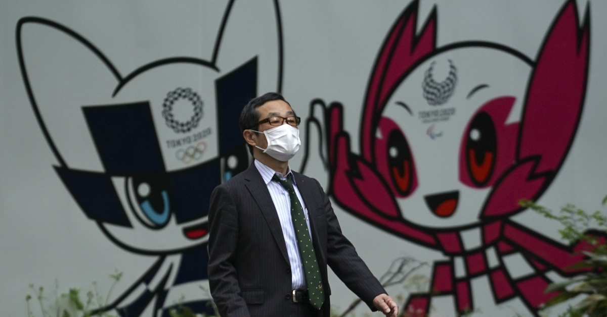  在东京，一名男子戴口罩自我防御；他的背景正是东京奥运会和东京残疾奥运会的吉祥物。 （法新社）