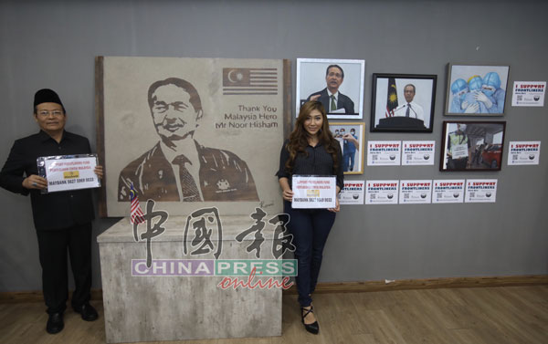 陈嘉慧（右）捐赠由她精心绘制的6幅画作，希望民众能响应“用艺术守护前线英雄”筹款活动。左为祖卡菲里。