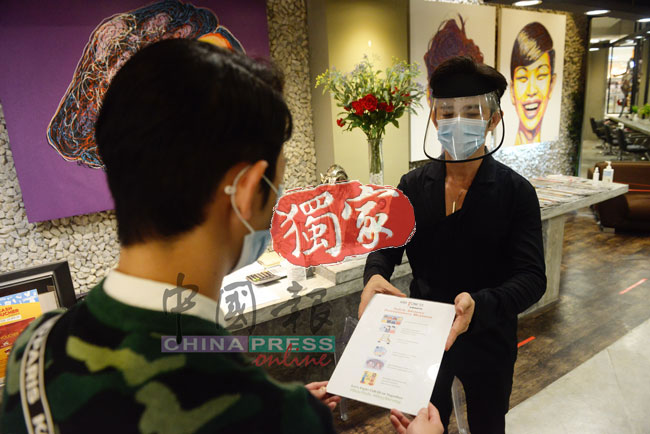 傅俊翔示范向顾客展示店内采取的防疫措施通知。