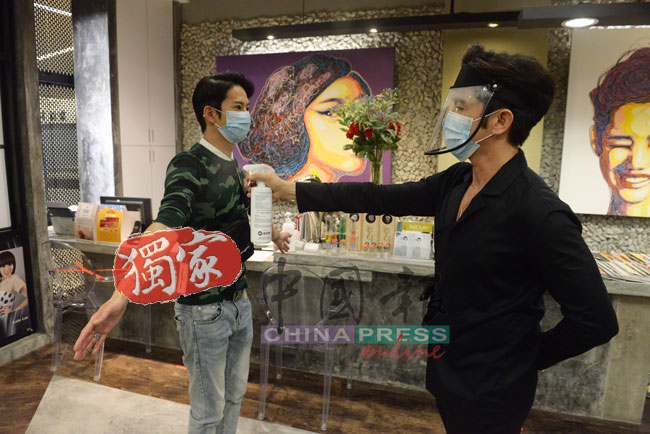 傅俊翔（右）示范使用银离子消毒喷雾为顾客进行全身消毒。