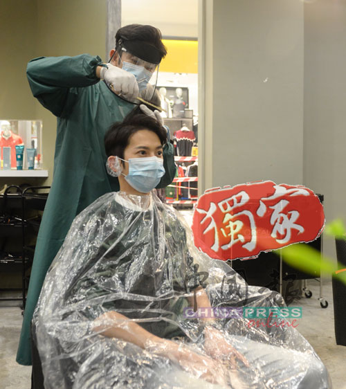 傅俊翔示范在穿上个人防护装备后，为顾客理发。