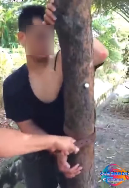 民众以裤带将匪徒的手捆绑在树干上。