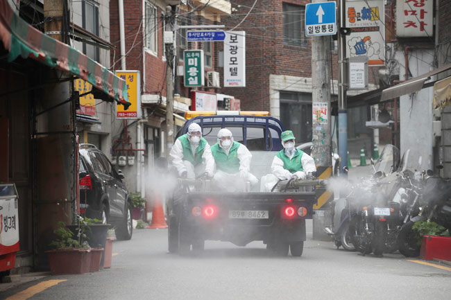 身穿防护服的工作人员， 周二在首尔的街道进行消毒工作。（美联社）