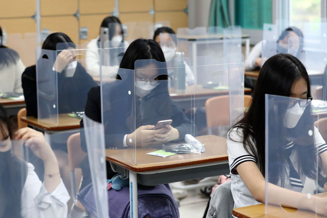 韩国大德区的高三学生周三复课，每张桌子都设置了塑料隔板，确保学生安全。（美联社）