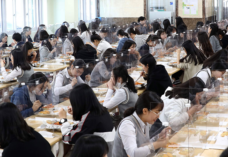 韩国大田市一所高中的学生，周四在食堂吃午餐时，餐桌上装置了透明隔板，以防止飞沫引起的病毒传染，降低感染新冠肺炎的风险。（法新社）