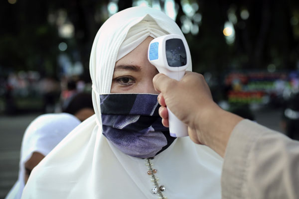 一名女穆斯林在进入拜图拉赫曼大清真寺祈祷之前， 接受保安人员为她测量体温。（美联社）