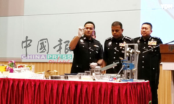 在许国振（右起）陪同下，阿育甘和查案官展示警方起获的毒品和制毒工具。