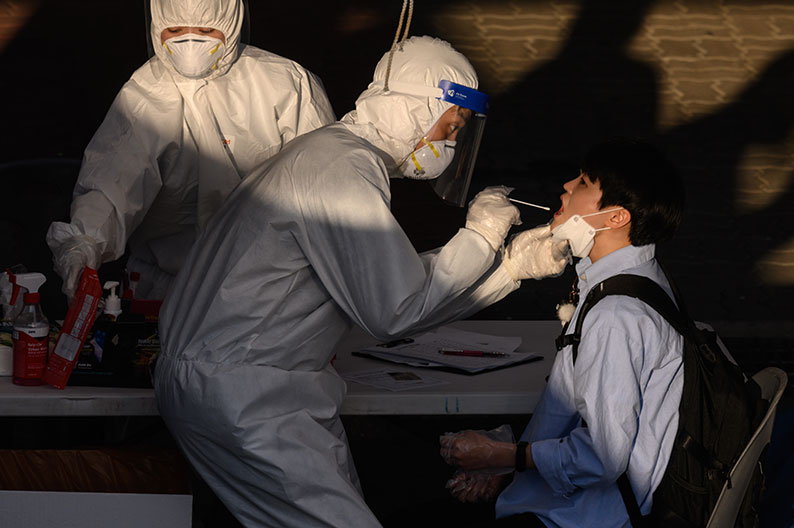 身穿防护服的卫生工作人员，周三在韩国富川市为民众进行新冠病毒拭子检测。（法新社）