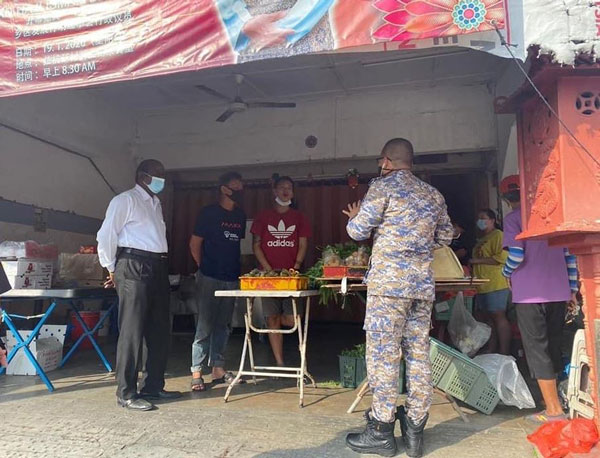 拉杭新村早市小贩在管制令期间冒险开摊摆卖，被闻讯而来的市政局官员取缔。