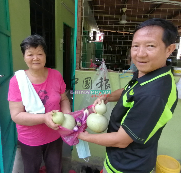 张桂兰（左起）送茄子及葫芦给邻居黄渶禄，分享蔬菜收成的喜悦。