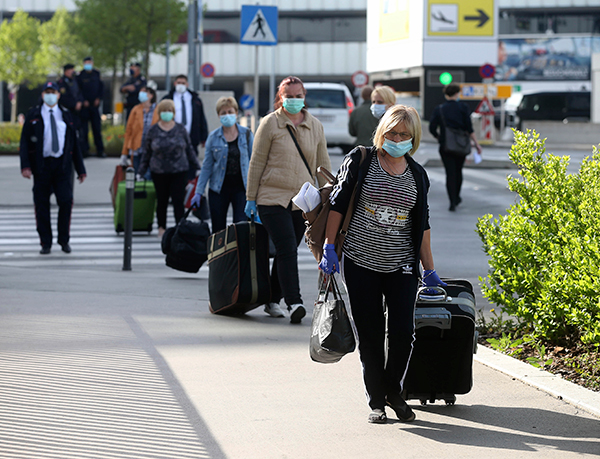 罗马尼亚护理工作者戴口罩，周一搭乘火车抵达奥地利国际机场后， 在警察和保安的护送下走出火车站月台。（美联社）