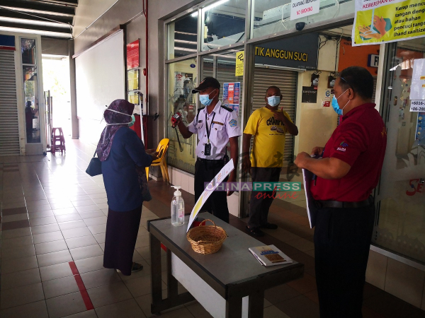 ■保安人员在入口处，为乘客测量体温。