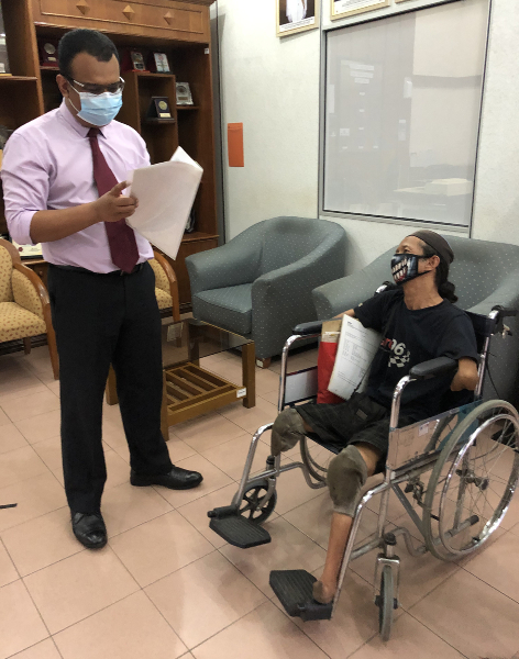 莫哈末菲道勿斯（站者）检查一名残障人士所要处理的文件。