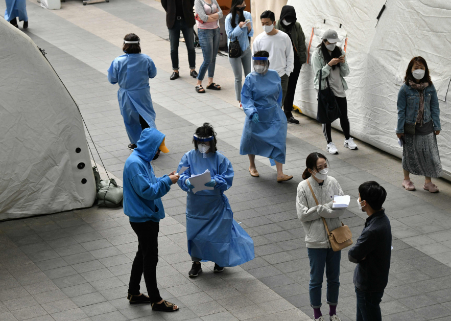 周二在首尔夜店区梨泰院区，医护人员为民众进行新冠肺炎病毒检查。（法新社）