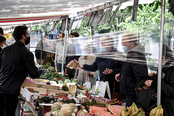 法国周二进入解封第二天，巴黎菜贩与民众隔着塑料膜进行交易。