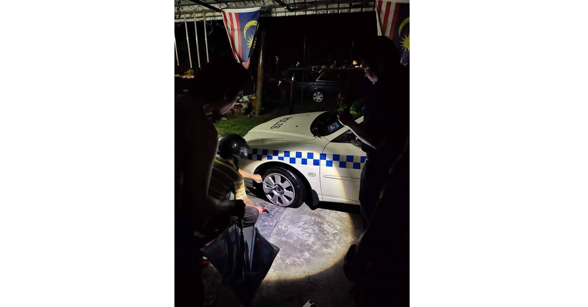 一名公众在手电筒的灯光下，更换警车的轮胎。（图取自Penang Kini）