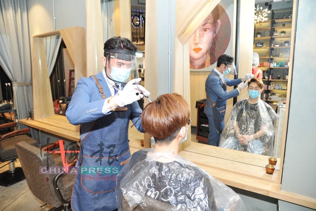 傅俊翔（左）与其员工示范美发师工作的标准作业程序。