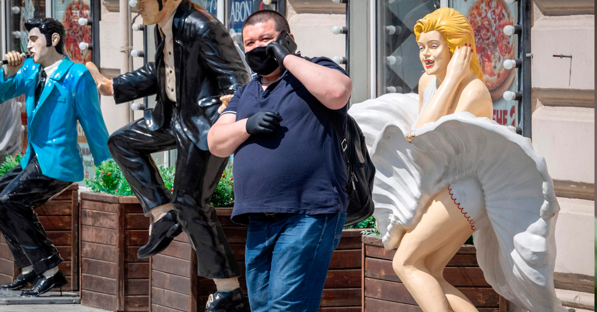 周一在莫斯科街头，一名穿戴口罩和手套的男子在打电话。