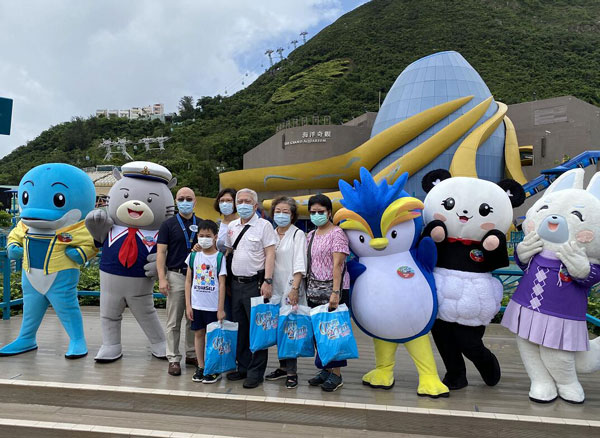 香港海洋公园周六重开，游客戴上口罩和园内吉祥物合照。