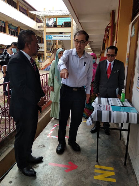 马汉顺（左2）向慕查化沙理科中学校长峇哈鲁（左）了解该校的开学准备。