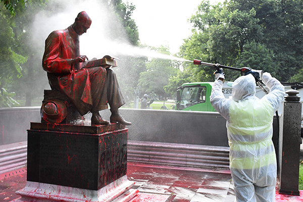 米兰市一名工人周日上午试着以喷雾清洁雕像。