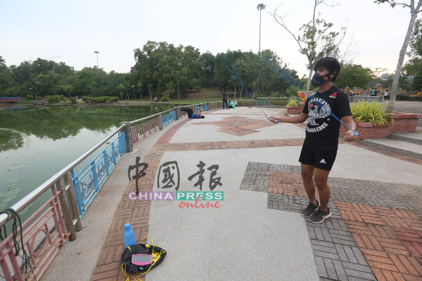 一名青年在湖边跳绳时，也做足防护措施自我保护。