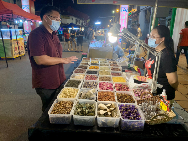 颜天禄（左）在巡视夜市时，向商贩业者了解重新开业的情况。
