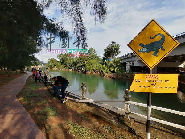 尽管吉双河岸设有“小心鳄鱼”的告示牌，民众若无其事地欣赏河边美景。 