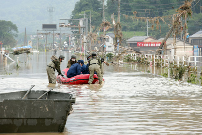 日本熊本縣的搜救人員用橡皮艇載老人院的老人撤離災區。（歐新社）