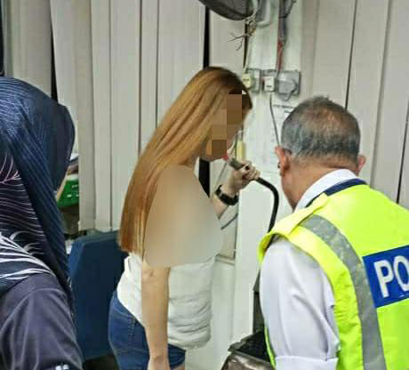 女子在首轮的酒气检测超标后，被警方带返警局进行第2轮检测。