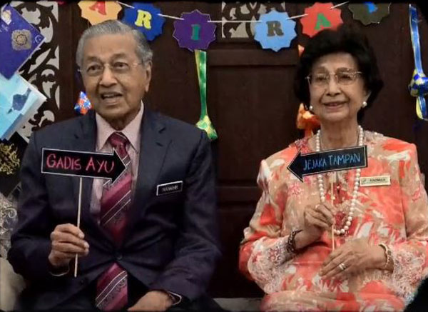 马哈迪（左起）和西蒂哈丝玛举着指向对方的“帅哥”和“美女”纸牌。