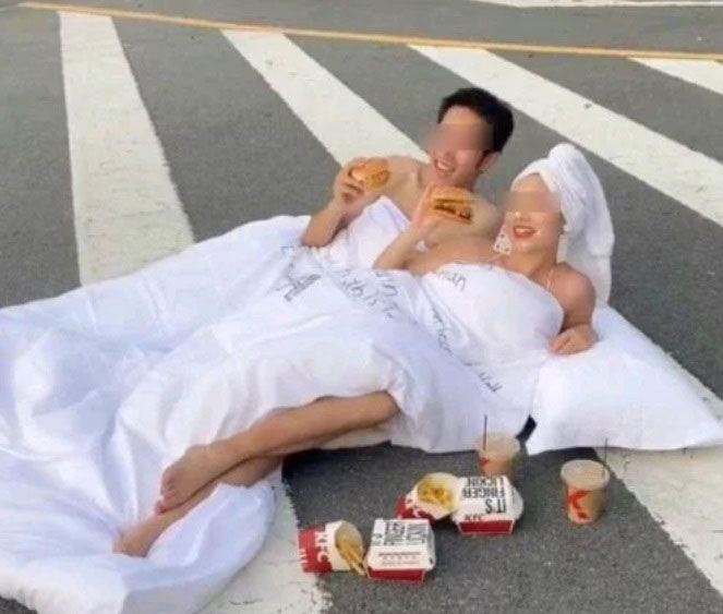 中国新人裹着床单在马路上拍婚纱。