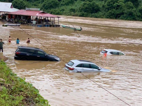 瓜拉大汉河水高涨，停泊在桥旁的数辆轿车被水淹没。