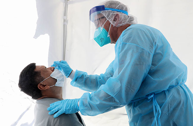 在美国南洛杉矶的一间流动诊所，一名医生周三为民众进行新冠病毒拭子检测。（法新社）