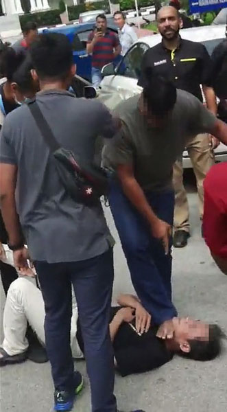 一名民众绊倒该男子后，一脚踩在其脖子上，防止对方继续发狂。