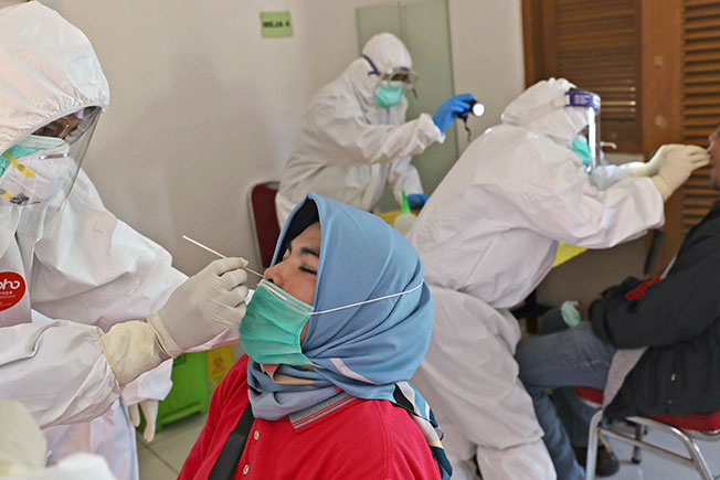 在印尼唐格朗社区，医护人员为民众进行新冠病毒检测。（美联社）