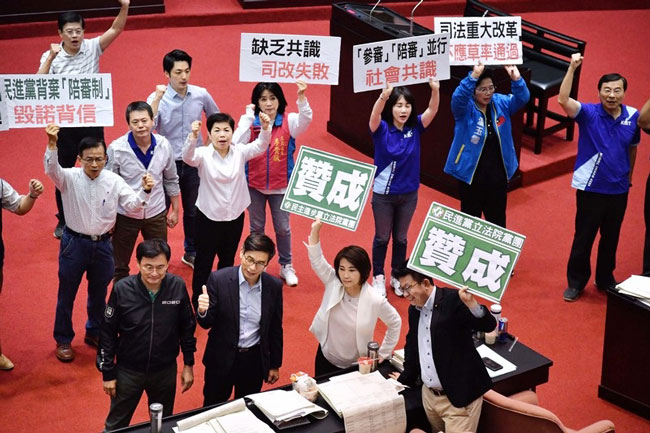 台湾立法院周三清晨二读通过国民法官法全部条文，国民党立委在议场持标语吁不应草率通过，民进党立委则高举赞成。（中央社）