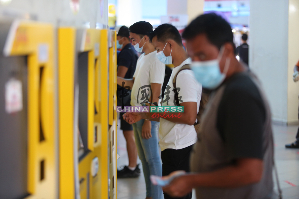 民众在自动售票机前戴口罩购买车票，疫情的程度取决于市民的防疫态度。