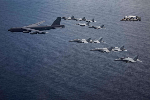 B-52轰炸机与F/A-18F“超级大黄蜂”战斗机、E-2“鹰眼”预警机在南中国海联合编队飞行的画面。