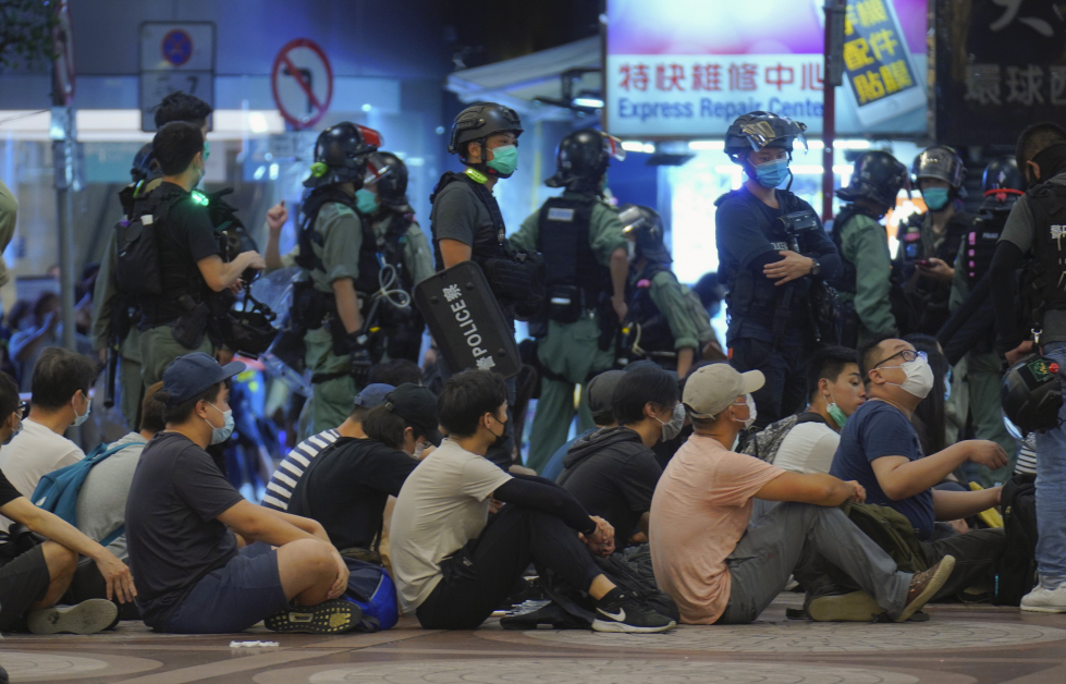 被逮捕的示威者坐在地上，等候警方处置。（美联社）